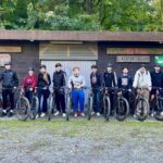 Schüler:innen der BBS Springe stehen mit Mountainbikes vor einem Holzhaus auf dem der Schriftzug "Naturfreundehaus Lauenstein" zu lesen ist.