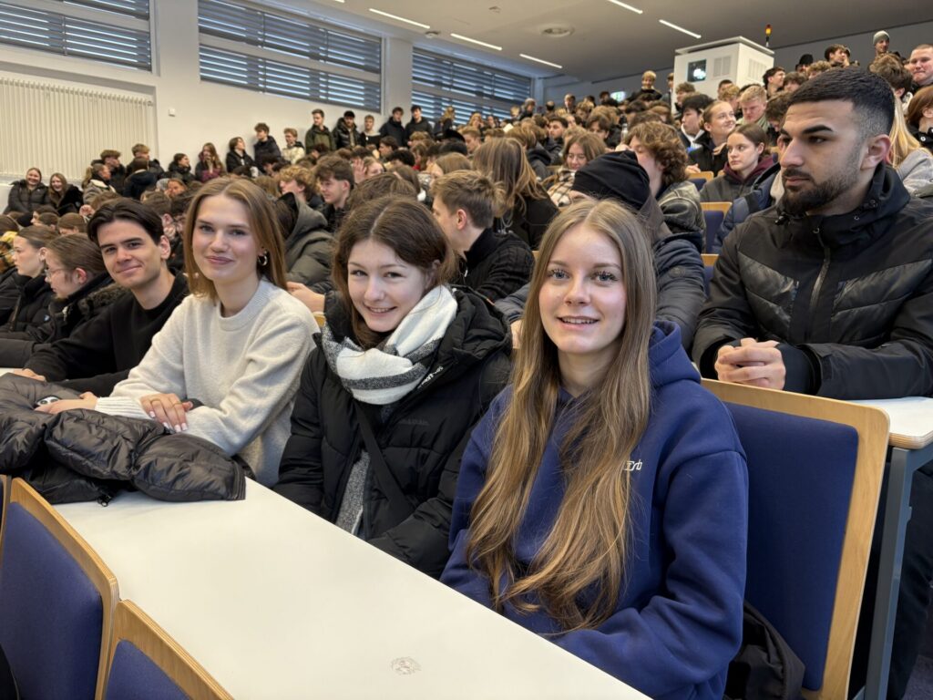 Schülerinnen und Schüler aus dem 12. Jahrgang besuchen sitzen in einem voll besetzten Hörsaal.